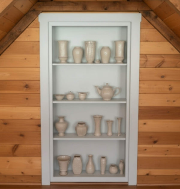 White bookshelf hidden door with ceramic vases against a wooden wall