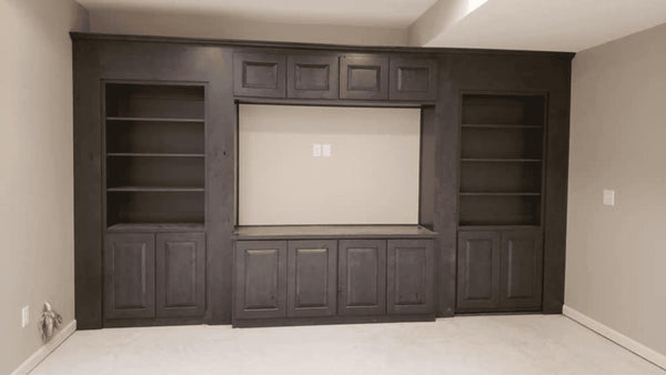 Built-in entertainment center with dark wood cabinets and shelves in a room.