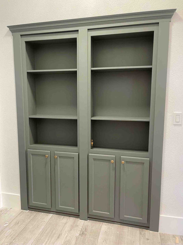 Gray hidden bookcase door with open shelves and closed doors against a white wall.