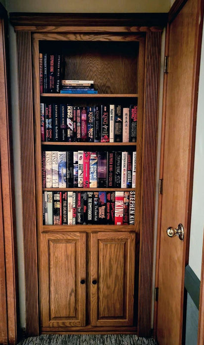 Hidden door bookcase red oak with shelves filled with books and cabinet doors at the bottom