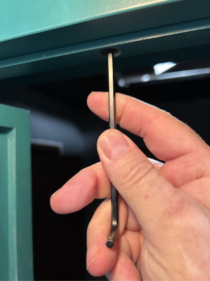 Hand installing hidden door top seal for out-swing doors on a green Hide-A-Way-Door frame