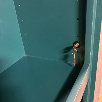 Mechanical key lock for hidden doors installed inside a teal cabinet with a key inserted
