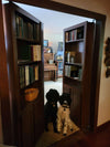 Hidden bookcase door by Hide-A-Way-Doors with shelves full of books and two dogs sitting inside the doorway
