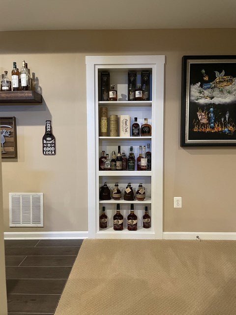 Hide-A-Way-Doors hidden bookcase door blending seamlessly into beige wall with liquor bottles displayed inside
